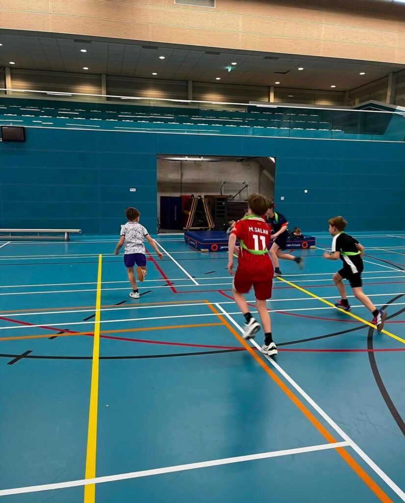 Kinderen rennen en spelen tikkertje bij Sport-BSO Flekss