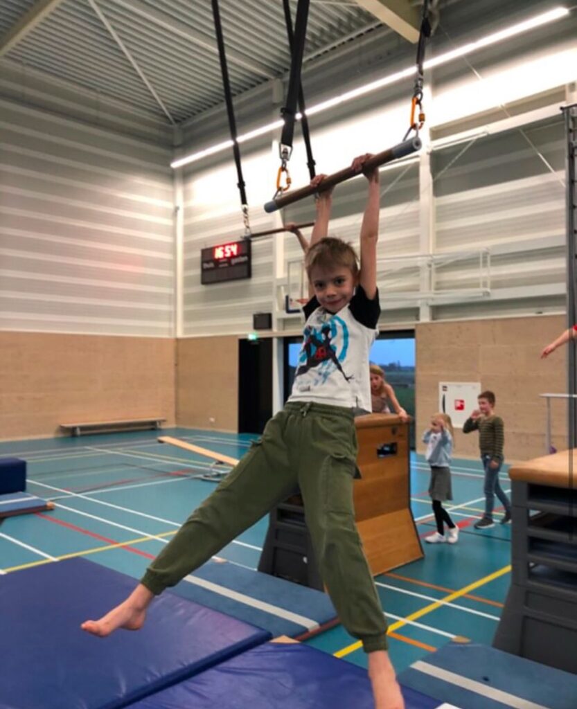 Kinderen zwaaien aan trapeze bij Sport-BSO Flekss