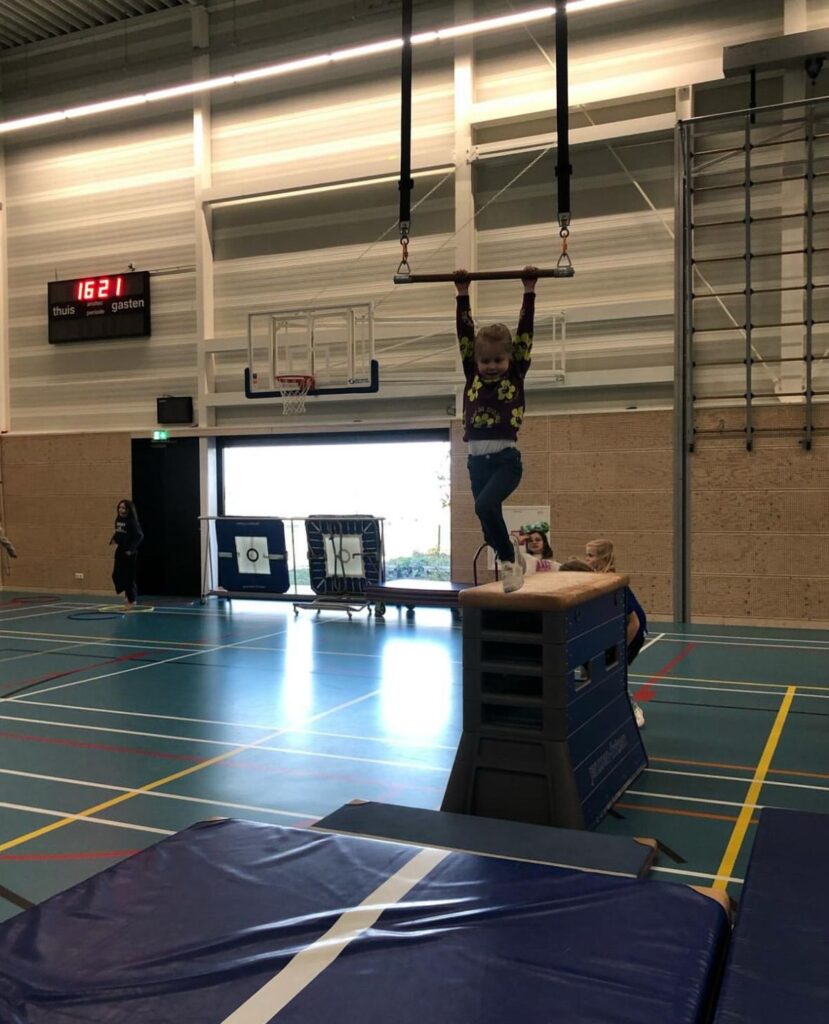 Kindje zwaait aan de trapeze bij Sport-BSO Flekss