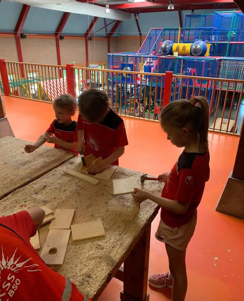 Kinderen timmeren een kunstwerk bij Sport-BSO Flekss