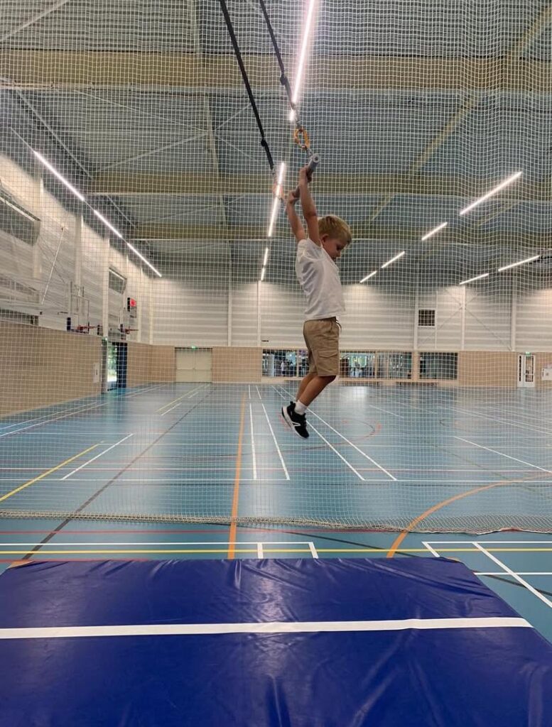 Kinderen zwaaien aan de trapeze stok bij Sport-BSO Flekss